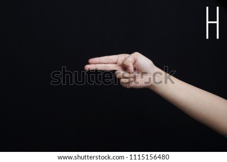 Finger spelling alphabet. Female hands isolated on blue background showing deaf mute BSL alphabet letter H                               