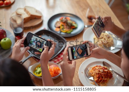 Close up hands of group of woman taking food photo by mobile phone on wood table in restaurant.