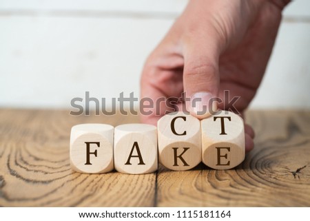 hand reveals that a "fact" is a "fake" by flipping two cubes Royalty-Free Stock Photo #1115181164