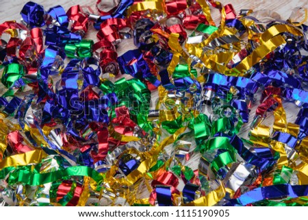 Multicolored confetti on a wooden background. Bright strips of colored foil. Colorful tinsel on holiday