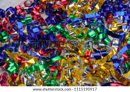 Multicolored confetti on a wooden background. Bright strips of colored foil. Colorful tinsel on holiday