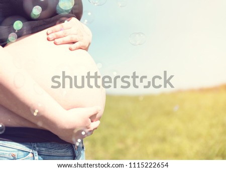 Beautiful pregnant woman relaxing with bubbles in grass