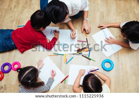 Top view Family happy children group kid boy and girl kindergarten paint drawing on peper with teacher education together at interior playroom Royalty-Free Stock Photo #1115225936