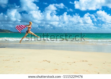 Patriotic woman american bikini weaving american flag. Female jumping in tropical Hawaiian beach. Lanikai Beach in Oahu, Hawaii, USA. Freedom and 4th July patriotic concept in Indipendence day.