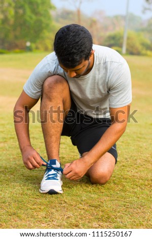 Young guy tying shoe laces and getting ready to run 