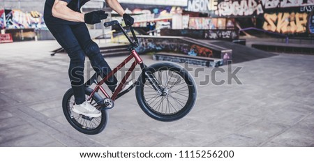 Cropped image of teenage BMX rider is performing tricks in skatepark.