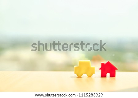 Car model and house model on wooden boards.Have a background office.Credit or loan and earning for home in the family.Use money to exchange or buy in business and real estate.          