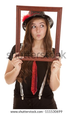A teen girl showing her fun side by holding up a picture frame with a pucker on her lips.