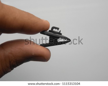 Hand of man holding small black color earphone wire clip
