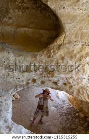 woman takes a picture with cellphone in a cave in matala, crete, greece