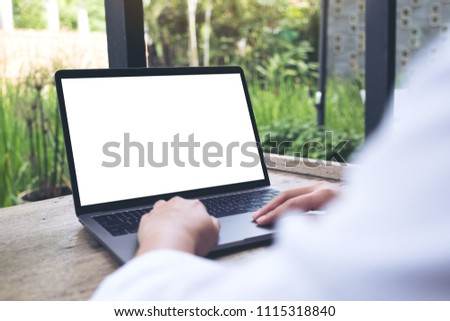Mockup image of a woman using and typing on laptop with blank white desktop screen with nature background