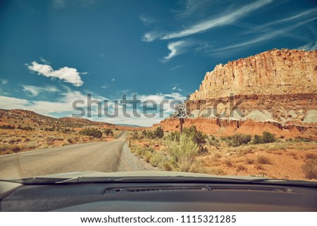 Retro toned picture of a road seen through a windshield, travel concept.