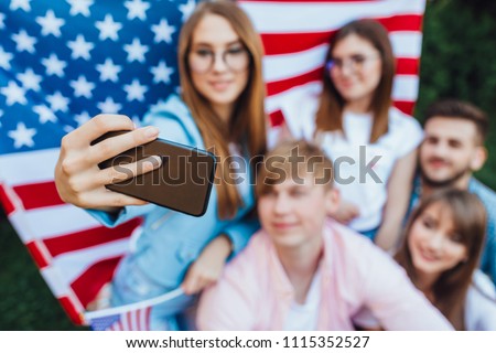 This is the US Independence Day! A group of young Americans doing sephi against the background of the American flag. Mobile phone close up.