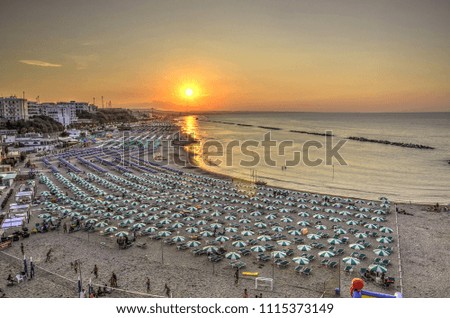 Sea panorama of seaside resort with beach and umbrellas at sunset seen from above 