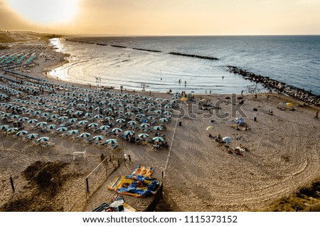 Sea panorama of seaside resort with beach and umbrellas at sunset seen from above 