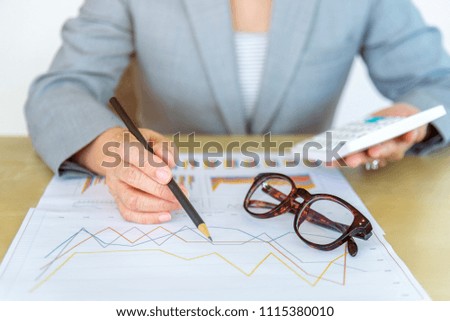 working woman holding pencil working with laptop, calculator and report data on wood desk in office.