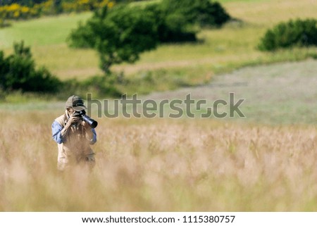 photographer, while taking naturalistic photos in the countryside among the flowers, green background