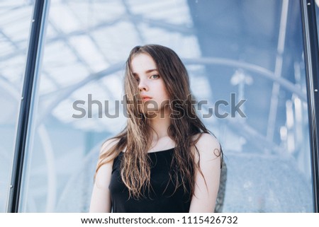 Close up outdoor portrait of a young cheerful natural caucasian stylish girl with wet long hair near glass building