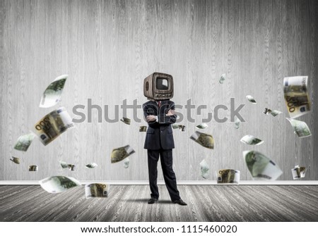 Businessman in suit with old TV instead of head keeping arms crossed while standing among flying euro banknotes inside empty room with gray dark wall on background.