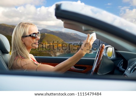 travel, road trip and people concept - happy young woman in convertible car taking selfie by smartphone over big sur coast of california background
