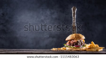 Close-up home made beef burger with knife and fries on wooden table.