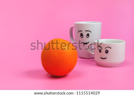 White ceramic mugs with painted funny faces and fresh fruit, healthy food, benefits and vitamins. Orange.