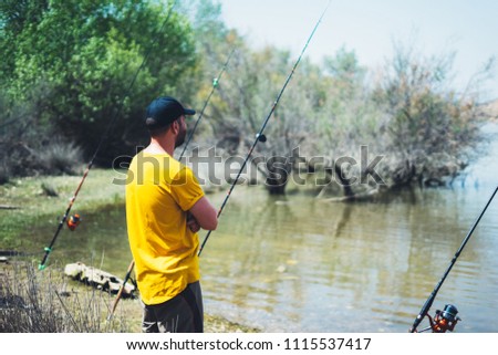 young man looking on horizont seascape and holds a fishing rod and catches fish in the nature background, hipster fisherman spends vacation on the blue ocean, active travel hobby fishing