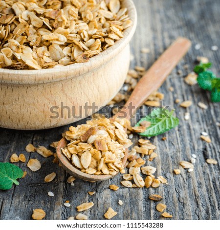 Healthy cereal snacks. Fitness dietary super food. Homemade granola. Baked flakes in wooden bowl on old rustic wooden board. Wooden spoon nearby. Vegetarian vegan nutrition concept. Square.