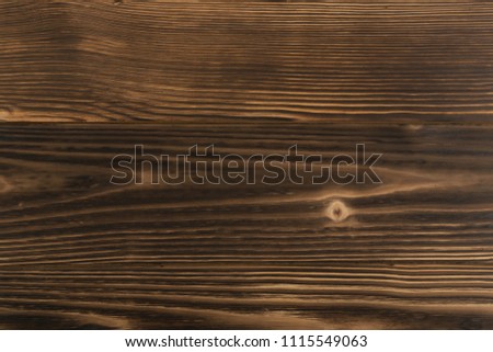 Old dark burnt wood background. Scorched wooden board plank texture. Natural rustic photo backdrop for vintage hipster design