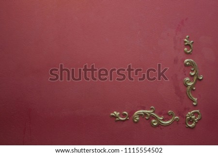 Frame of a golden flower at a corner of a burgundy painted wall