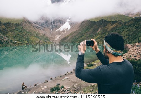 Tourist exploring natural environment of mountains covered clouds on modern smartphone device during wanderlust.Traveller shooting video of amazing nature in Salkantay on digital cellular