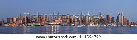 Hudson River waterfront view of New York City Manhattan after sunset with cityscape panorama and light reflection in tranquil blue tone.