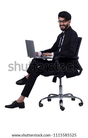 Young man wearing suit sitting on office chair working on his laptop smiling, isolated on a white background.