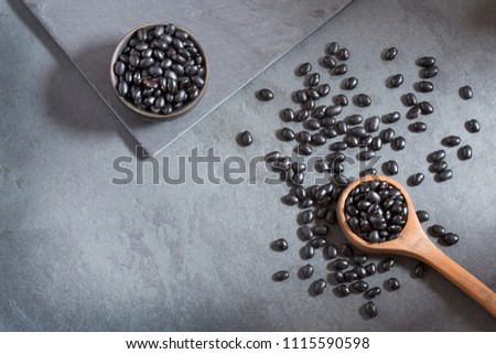 Raw black beans on the wooden background