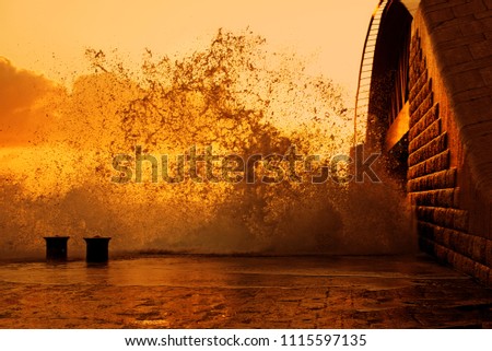 Huge waves in stormy morning near Valletta new harbor bridge, Malta. Artistic photo of golden sunrise