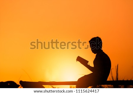 Boy reading holy bible on wood , christian silhouette concept.