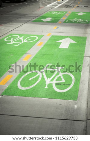 Green and white bicycle symbol on a city street, for protected urban bike lanes