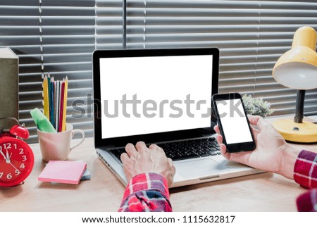 Office desk mockup concept.Man's hands using blank screen laptop and blank screen smart phone  in modern office.