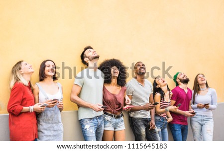 Multiracial friends having fun using smartphone at wall on university college break - Young people addicted by mobile smart phones - Technology concept with always connected millennials - Filter image