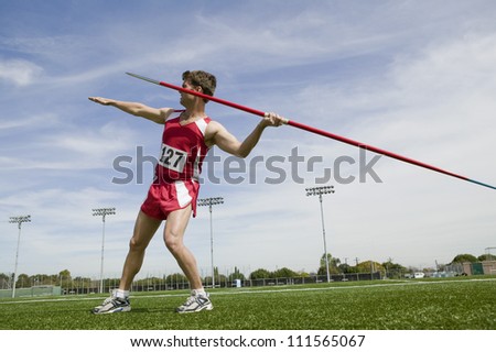 Full length of man with arm extended about to release javelin Royalty-Free Stock Photo #111565067