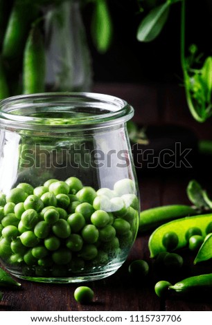 Green peas in glass jar, brown background, selective focus