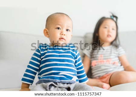 Little baby boy and little girl sister  watching cartoon TV together at home and having fun together.Family with children at home.