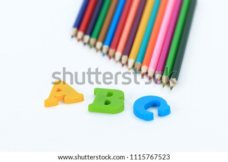 colored pencils and letters of the alphabet on a white background .photo with copy space