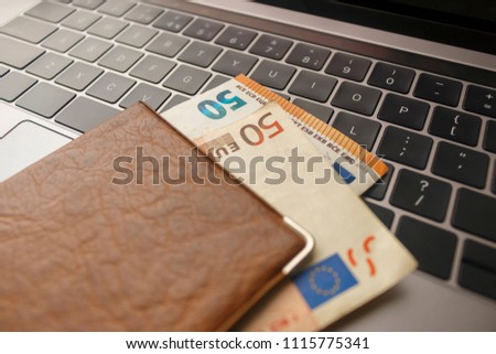 passport with euro banknotes lie on a black laptop keyboard