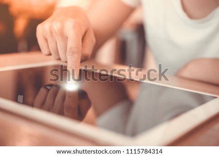 Woman hand using big tablet to do work, planning, reading in coffee cafe with bokeh light background.