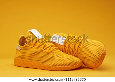 Yellow tennis modern shoes isolated on orange background Royalty-Free Stock Photo #1115795330
