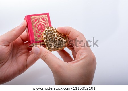 Hand holding Heart shape  and Islamic Holy Book Quran