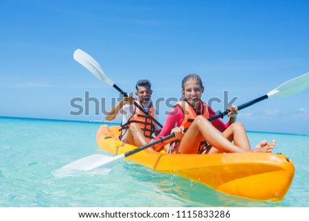 Happy cute girl and her father kayaking at tropical sea on yellow kayak Royalty-Free Stock Photo #1115833286