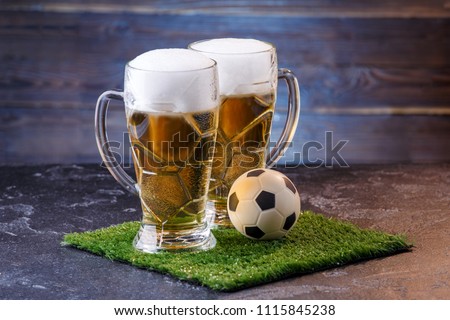 Photo of two glasses of beer, soccer ball on green grass