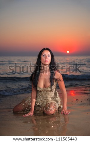 Beautiful young woman on the beach at sunrise